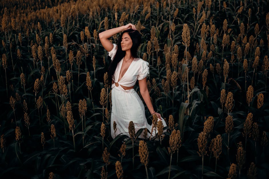 A woman in a white dress posing amidst a lush sorghum field in Brazil, exuding serenity.